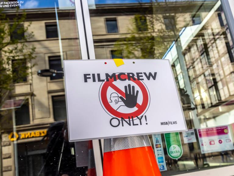 An einer Glastür ist ein Stoppschild mit der Aufschrift "Filmcrew Only!" angebracht.