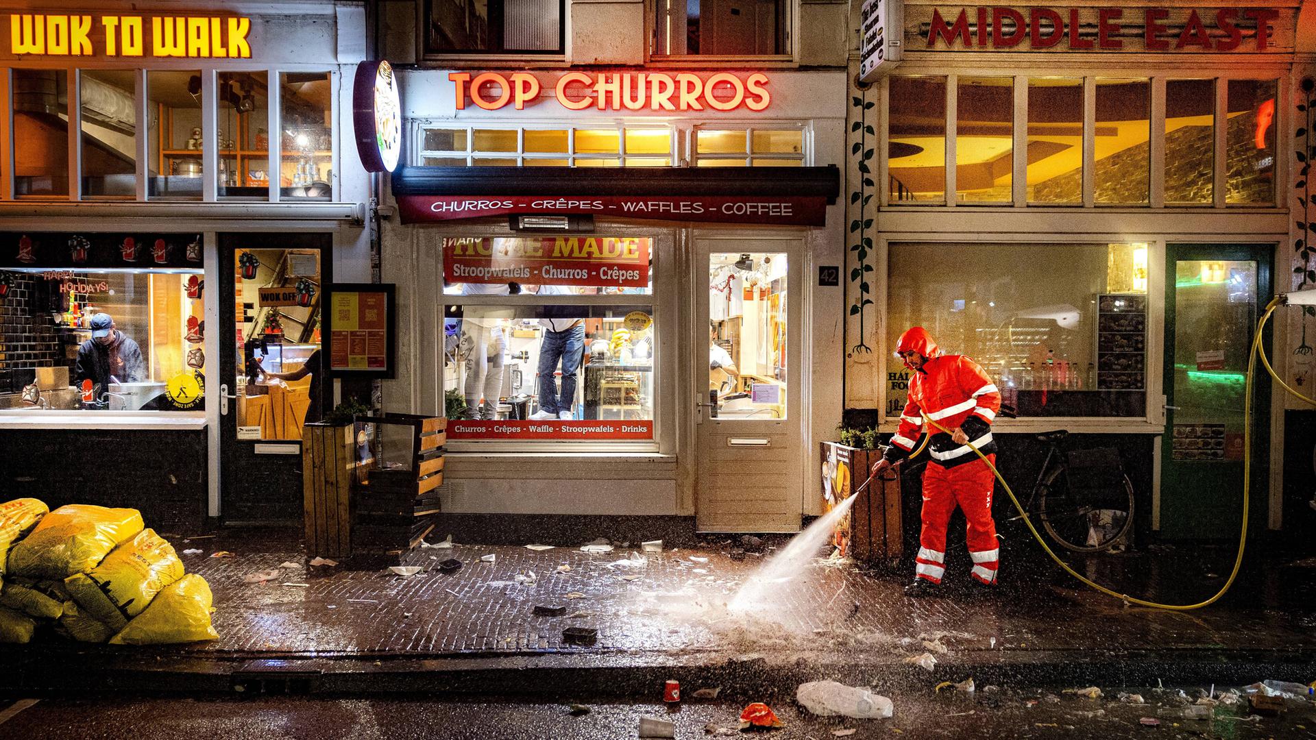 Silvesterchaos auf der Damstraat in Amsterdam. Die Reinigungskräfte sind am Neujahrstag 2024 früh unterwegs, um die Überreste der Silvesternacht zu beseitigen. Sie spritzen die Bürgersteige sauber. (Symbolfoto)