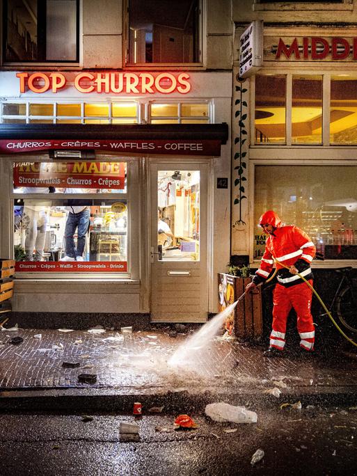 Silvesterchaos auf der Damstraat in Amsterdam. Die Reinigungskräfte sind am Neujahrstag 2024 früh unterwegs, um die Überreste der Silvesternacht zu beseitigen. Sie spritzen die Bürgersteige sauber. (Symbolfoto)
