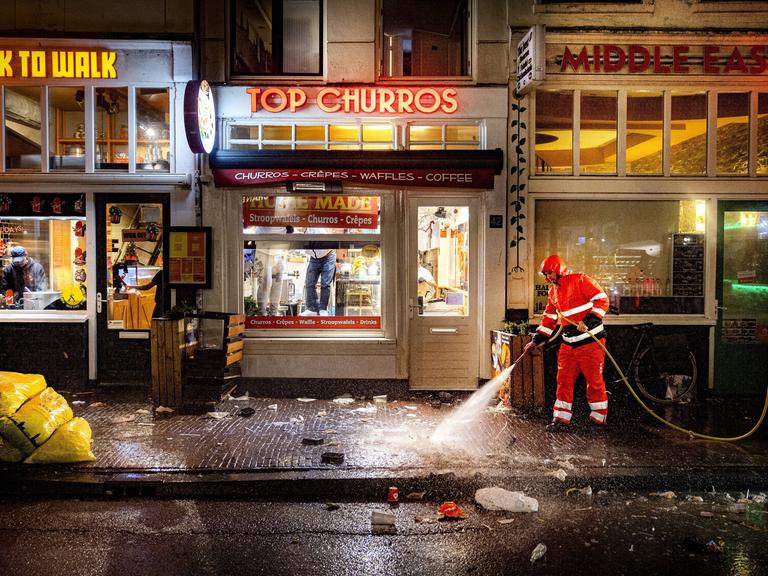 Silvesterchaos auf der Damstraat in Amsterdam. Die Reinigungskräfte sind am Neujahrstag 2024 früh unterwegs, um die Überreste der Silvesternacht zu beseitigen. Sie spritzen die Bürgersteige sauber. (Symbolfoto)