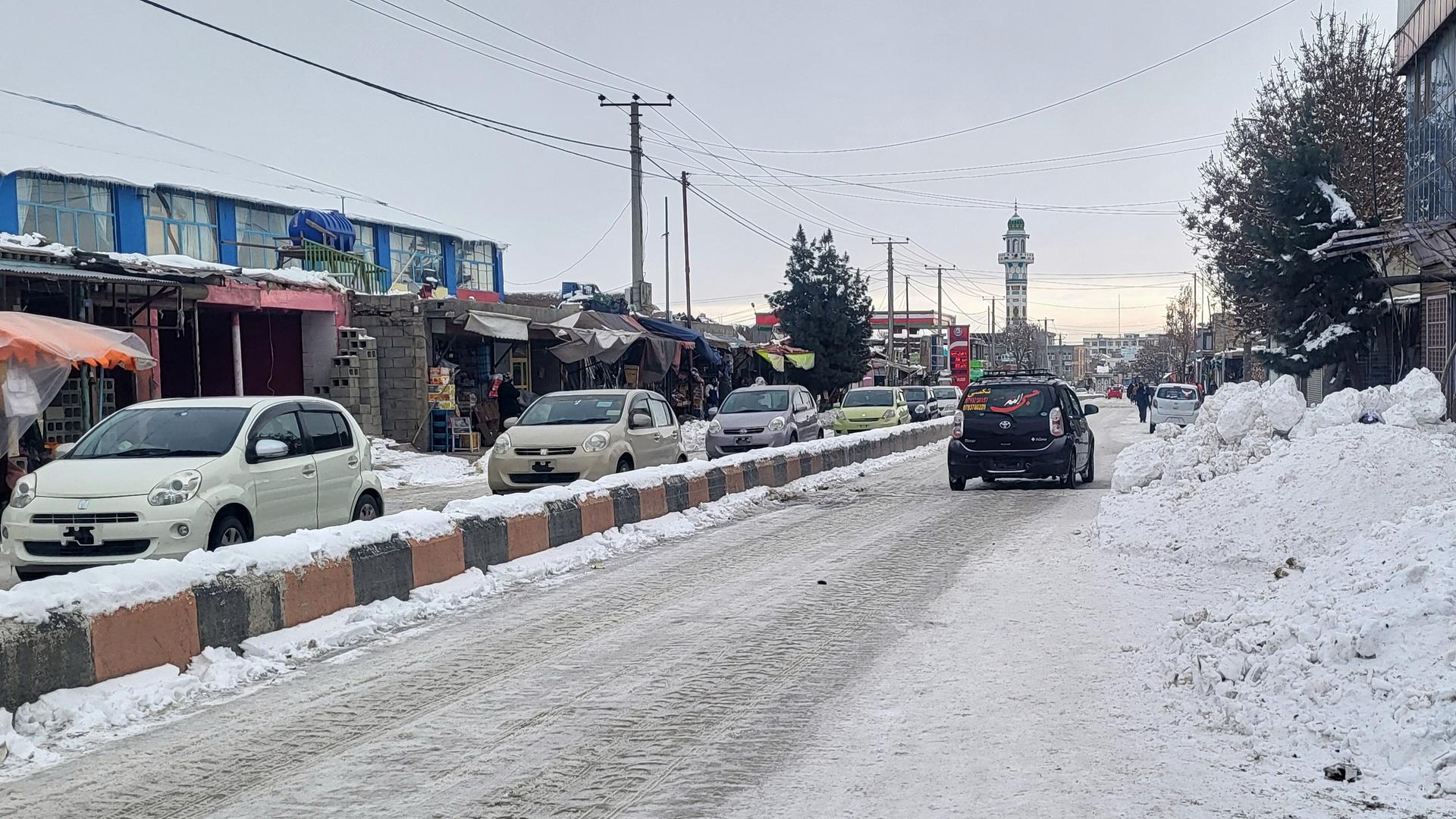 In einigen Provinzen Afghanistans gab es heftige Schneefälle; hier die Stadt Ghazni, südwestlich der Hauptstadt Kabul. Autos fahren auf einer schneebedeckten Straße; links sind Häuser mit Geschäften zu sehen.