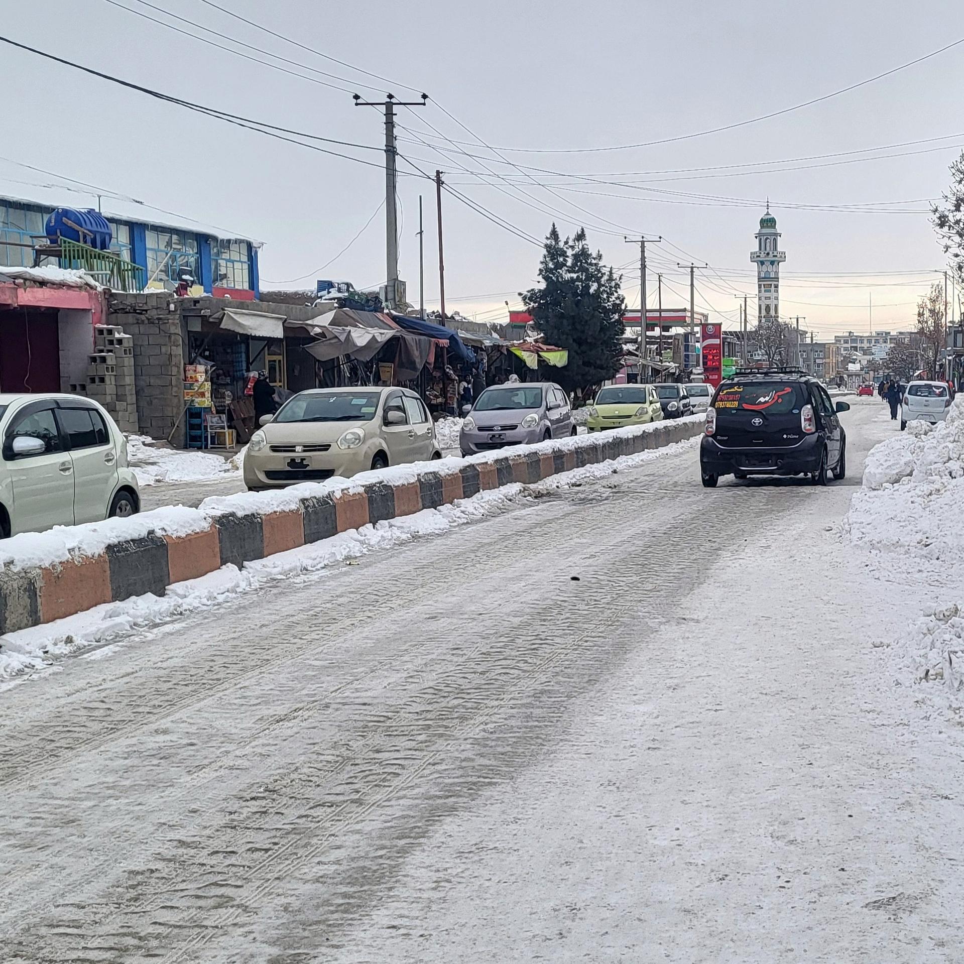 In einigen Provinzen Afghanistans gab es heftige Schneefälle; hier die Stadt Ghazni, südwestlich der Hauptstadt Kabul. Autos fahren auf einer schneebedeckten Straße; links sind Häuser mit Geschäften zu sehen.