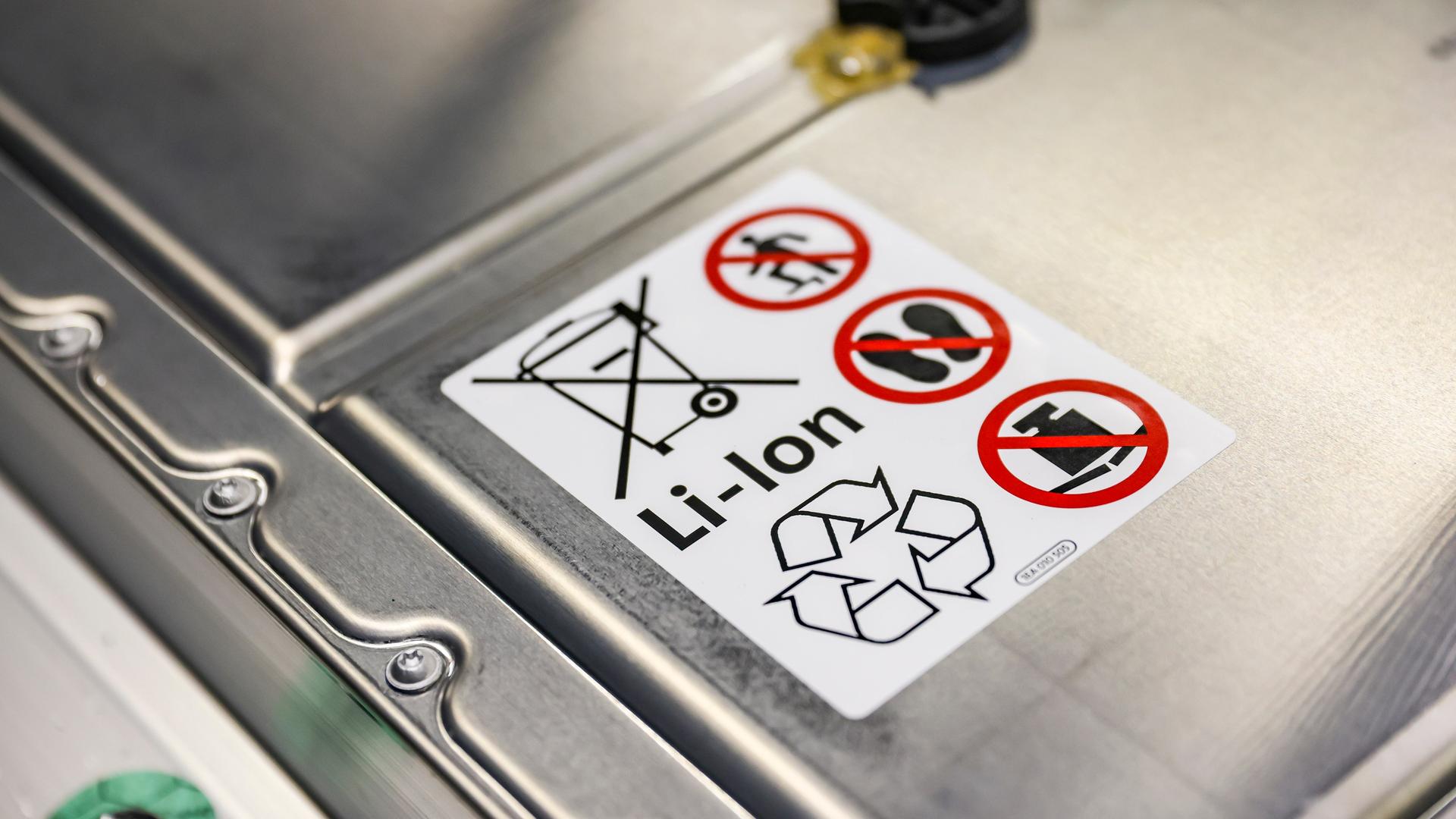 Der Lithium-Ionen-Akkumulator eines PKW. Auf der Batterie ist ein Aufkleber mit Warnhinweisen. Der Lithium-Ionen-Akkumulator eines PKW. Auf der Batterie ist ein Aufkleber mit Warnhinweisen.