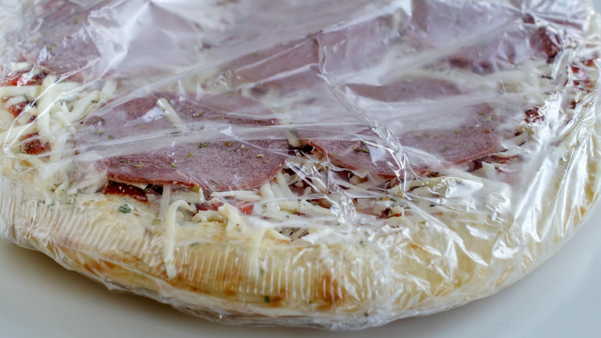 Tiefgekühlte Pizza aus der Packung als Convenience Food, noch in Folie verpackt