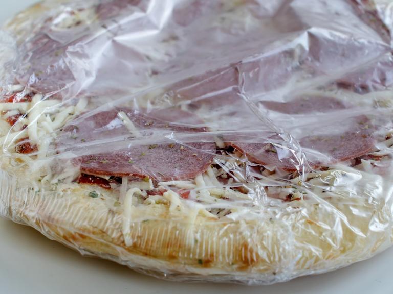 Tiefgekühlte Pizza aus der Packung als Convenience Food, noch in Folie verpackt