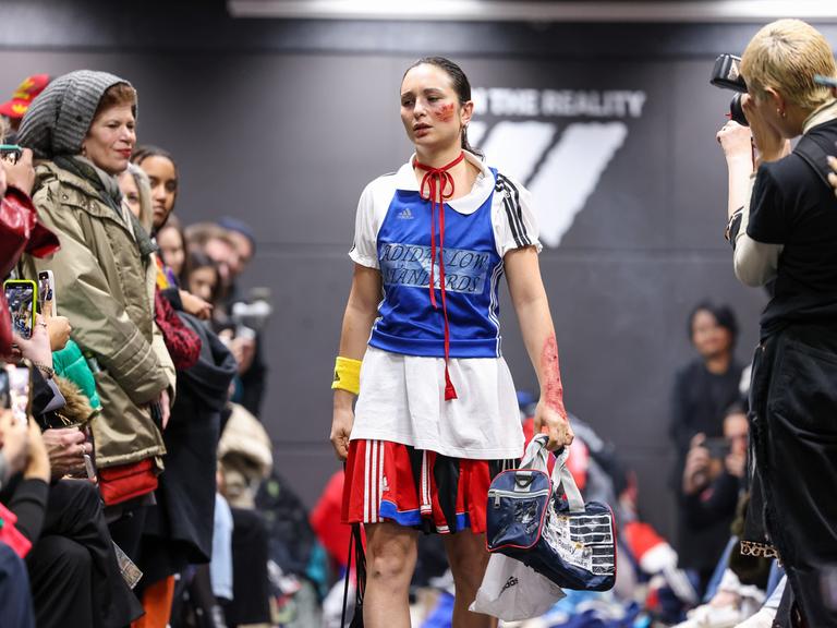 Eine Aktivistin geht bei einer als Adidas-Show getarnten Performance im Rahmen der Berliner Fashion Week über den Laufsteg. 