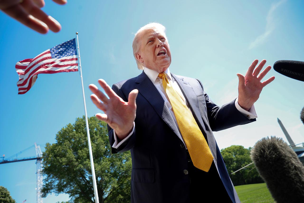 Der US-Präsident Donald Trump spricht mit Journalisten. Das Foto ist von schräg unten aufgenommen. Im Hintergrund ist eine US-Flagge und blauer Himmel zu sehen. Der US-Präsident Donald Trump spricht mit Journalisten. Das Foto ist von schräg unten aufgenommen. Im Hintergrund ist eine US-Flagge und blauer Himmel zu sehen.