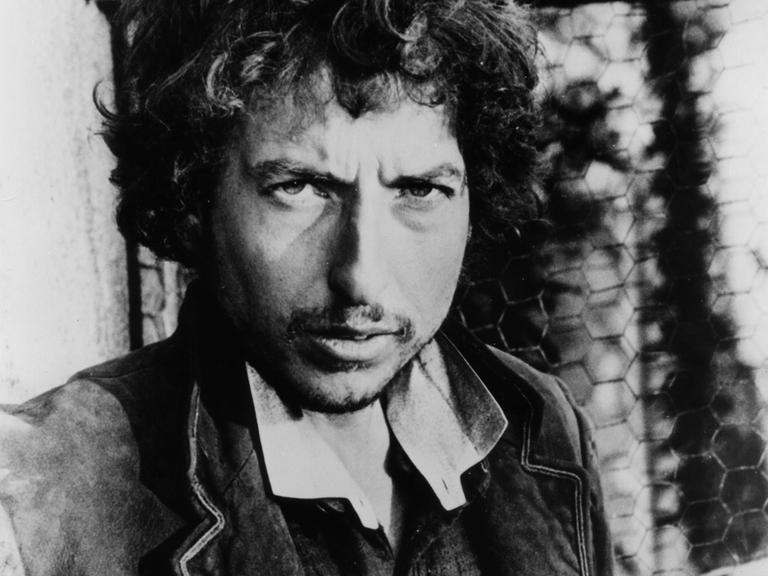 Schwarz-Weiß-Porträtfoto des US-Rocksängers Bob Dylan um 1975. Der Musiker schaut in die Kamera.