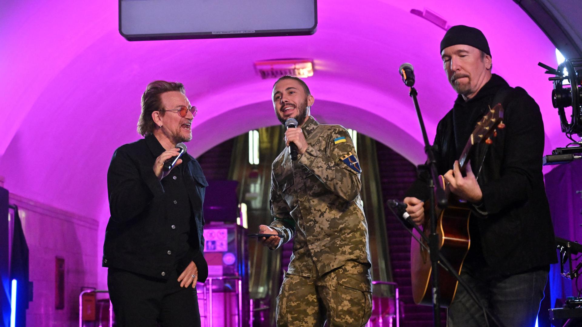 Drei Männer stehen auf einer Bühne und singen.