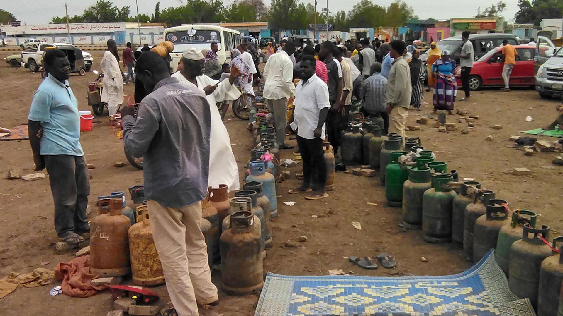 Menschen im Sudan stehen in einer Reihe und warten auf eine Gaslieferung, um ihre Kartuschen wieder befüllen zu können.