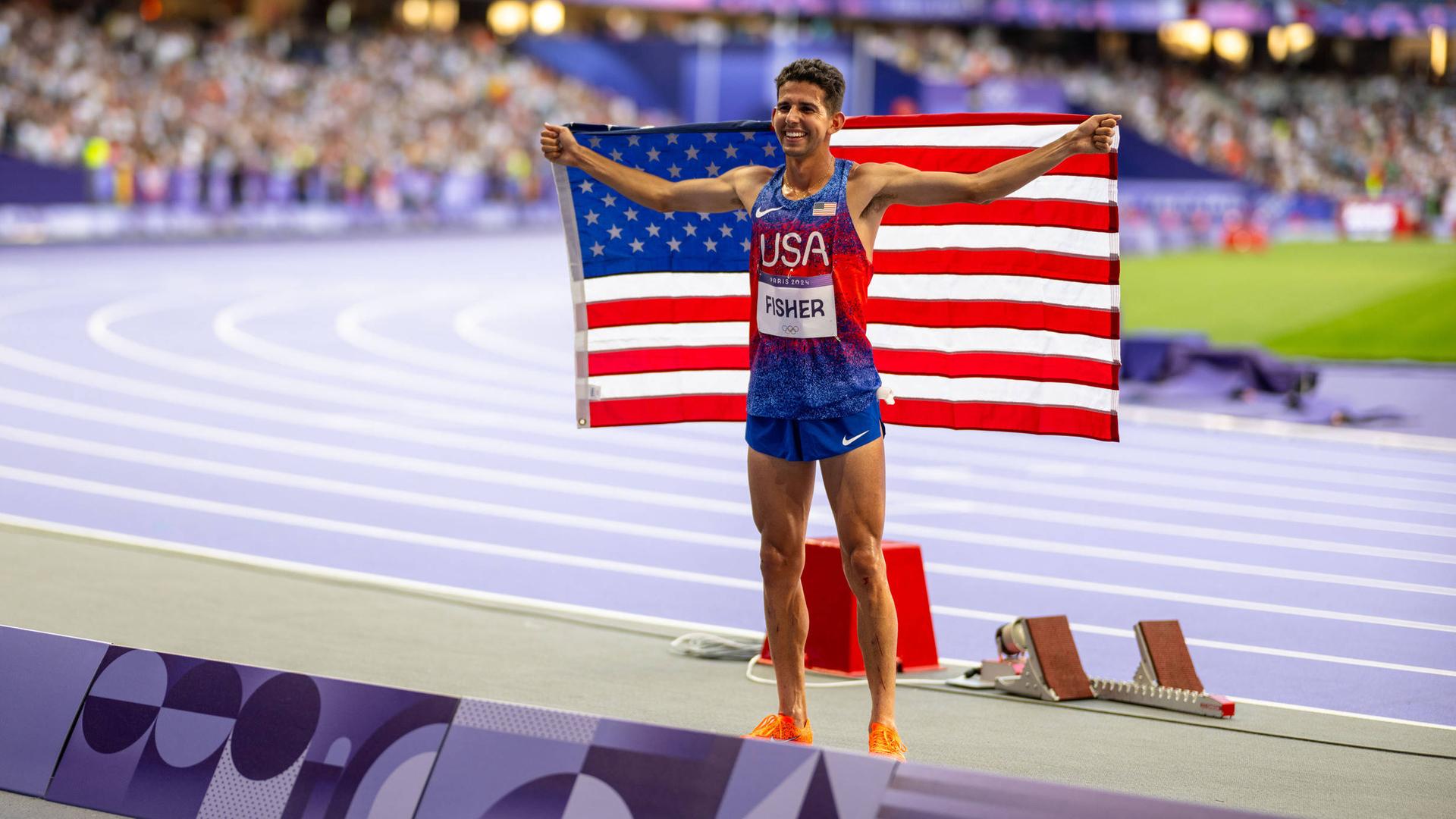 Das Foto zeigt den US-Sportler Grant Fisher bei den Olympischen Spielen in Paris im August 2024. Er hält eine US-Fahne in den Händen. Das Foto zeigt den US-Sportler Grant Fisher bei den Olympischen Spielen in Paris im August 2024. Er hält eine US-Fahne in den Händen.