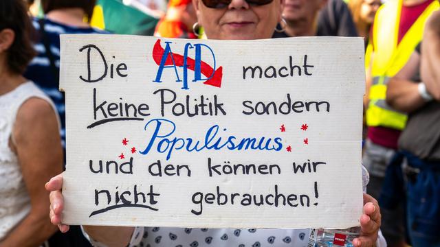 Eine Frau hält auf einer Demonstration ein Plakat in den Händen, auf dem steht: "Die AfD macht keine Politik sondern Populismus."