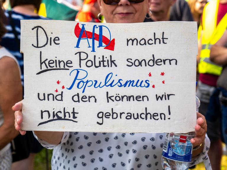 Eine Frau hält auf einer Demonstration ein Plakat in den Händen, auf dem steht: "Die AfD macht keine Politik sondern Populismus."