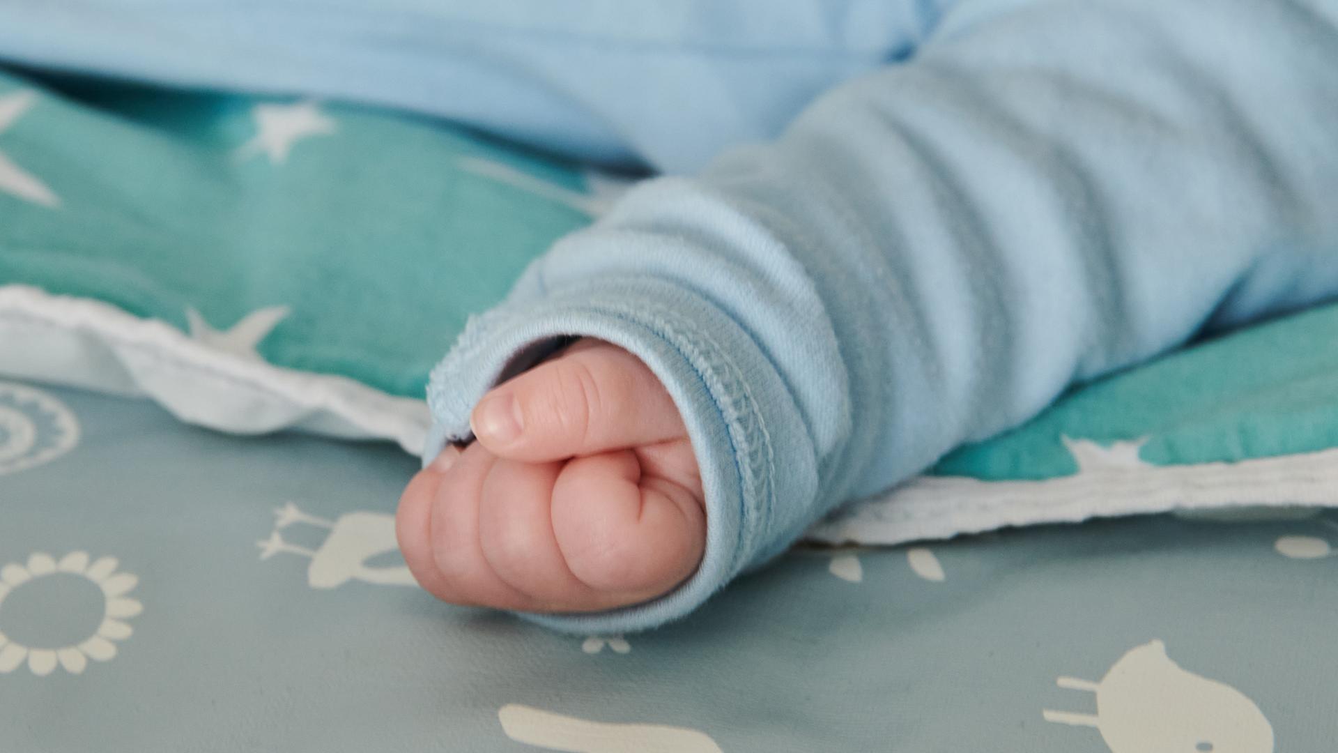 Die Hand eines nur wenige Wochen alten Babys ist zu einer kleinen Faust geballt.