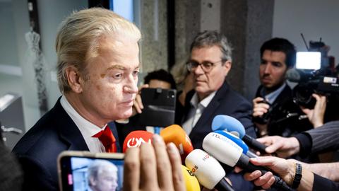 Geert Wilders steht vor vielen Reporterinnen und Reportern, die Mikrofone in seine Richtung strecken.