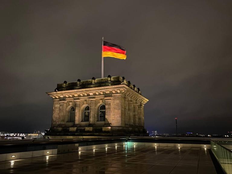 Die Deutschlandfahne auf dem Dach des Reichstages bei Nacht.