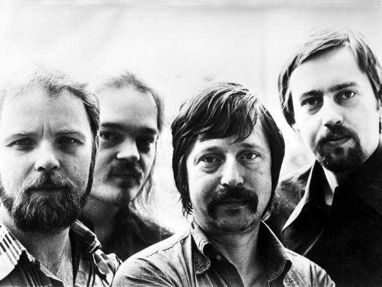 Gerulf Pannach, Christian Kunert, Wolf Biermann und Jürgen Fuchs auf einem historischen Foto von 1977. Sie lächeln in die Kamera. Gerulf Pannach, Christian Kunert, Wolf Biermann und Jürgen Fuchs auf einem historischen Foto von 1977. Sie lächeln in die Kamera.