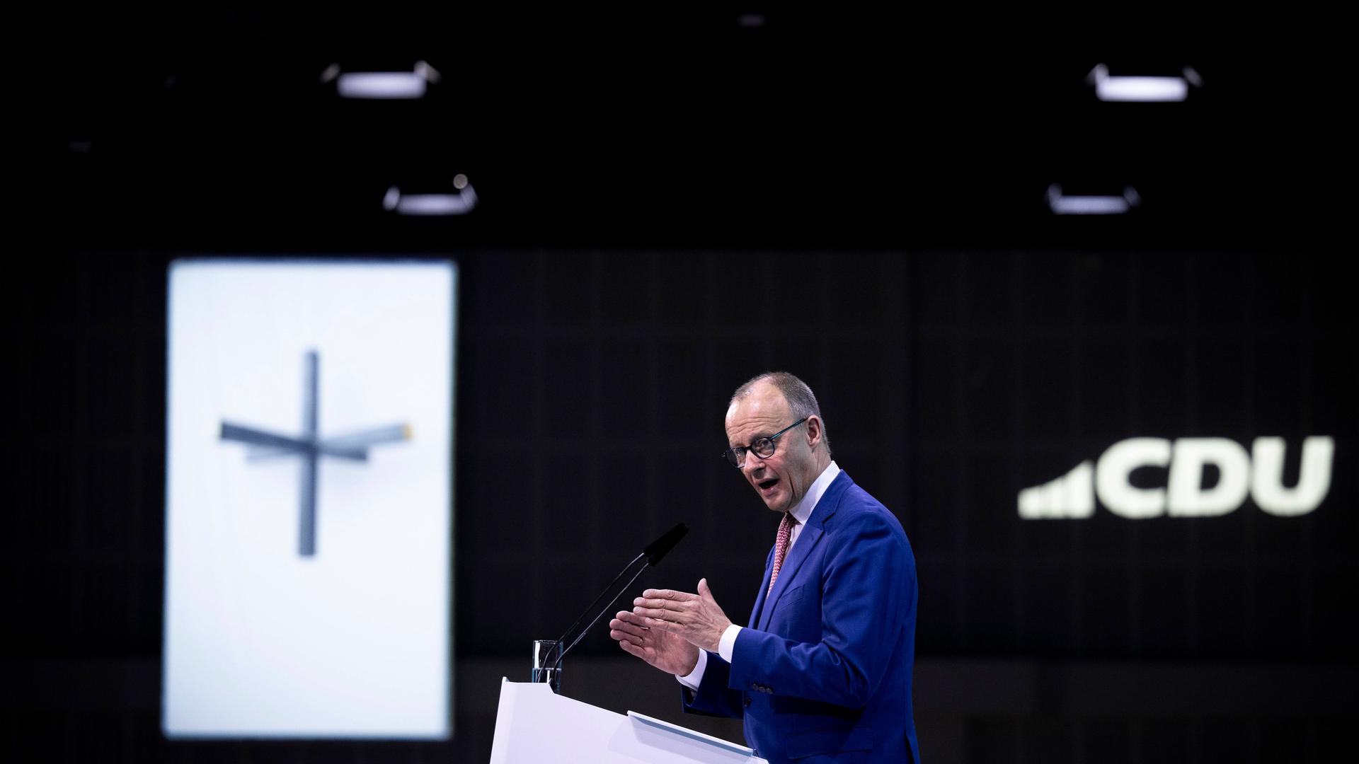 CDU-Chef Friedrich Merz steht an einem Rednerpult. Im Hintergrund ist ein christliiches Kreuz zu sehen.