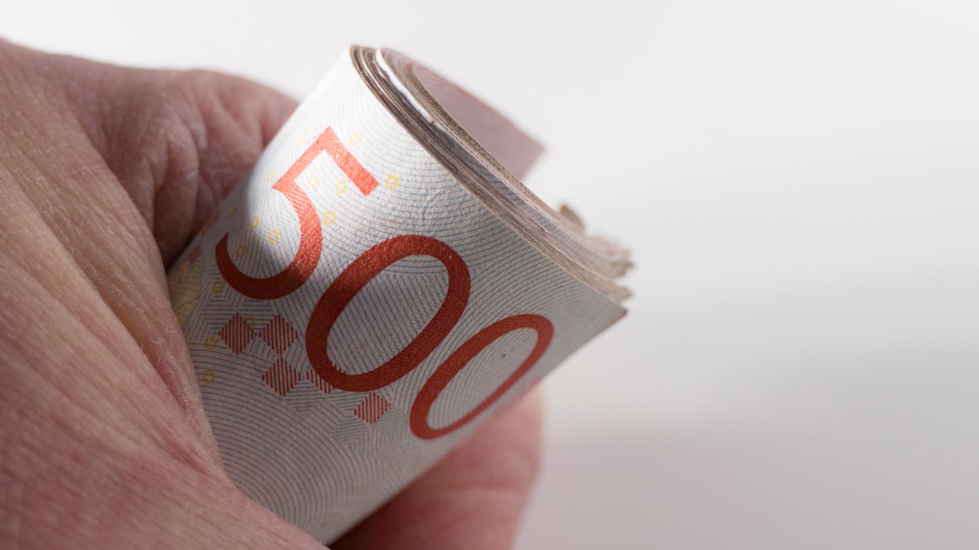 Eine Person hält eine Rolle schwedischer 500-Kronen-Scheine