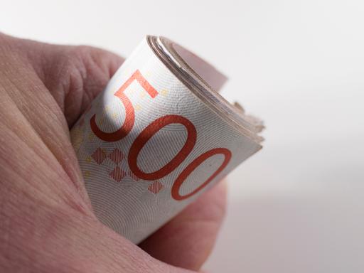Eine Person hält eine Rolle schwedischer 500-Kronen-Scheine Eine Person hält eine Rolle schwedischer 500-Kronen-Scheine
