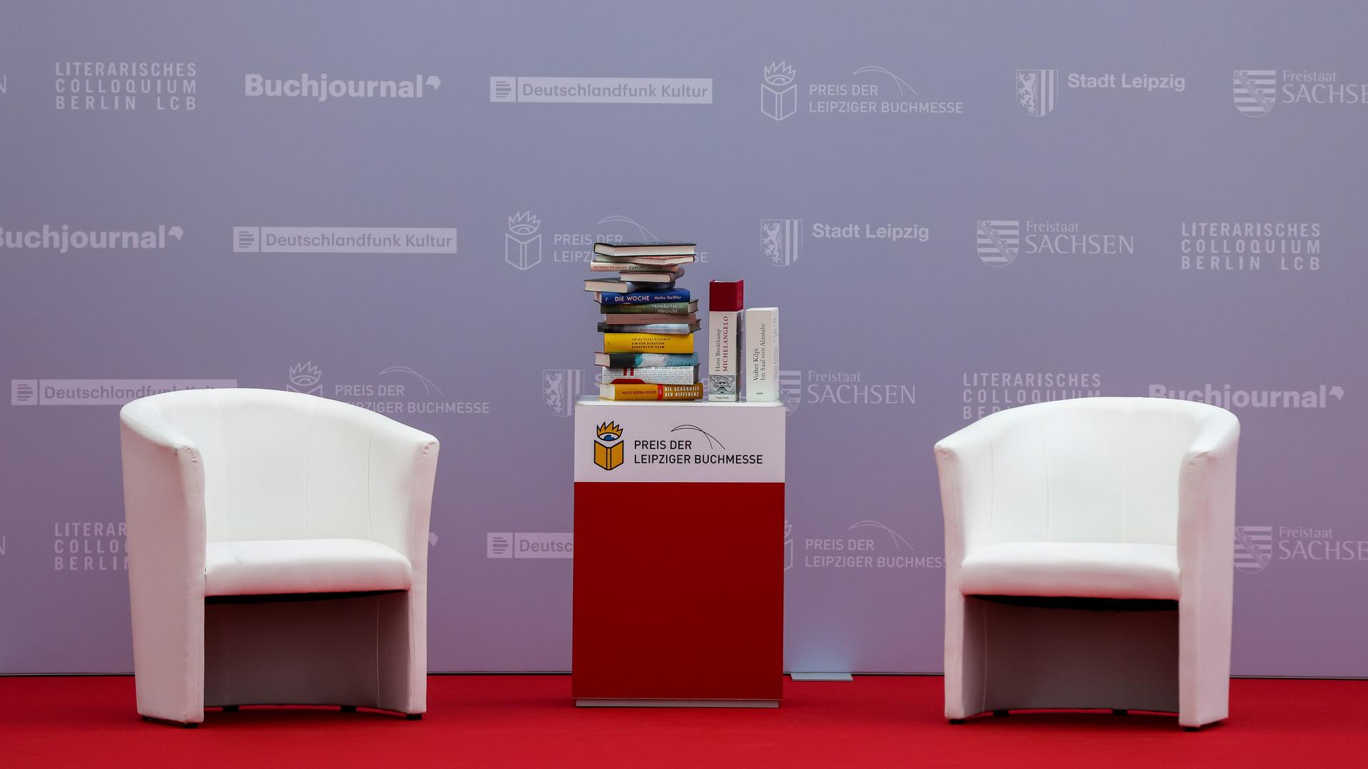 Zwei Sessel und ein Büchertisch stehen am Rande der Verleihung des Preises der Leipziger Buchmesse 2022 in der Glashalle der Messe.