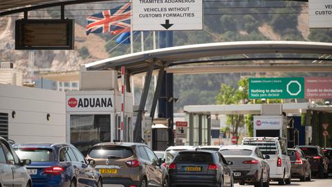 Fahrzeuge überqueren die Grenze von Spanien zu Gibraltar. Im Hintergrund weht die britische Flagge.