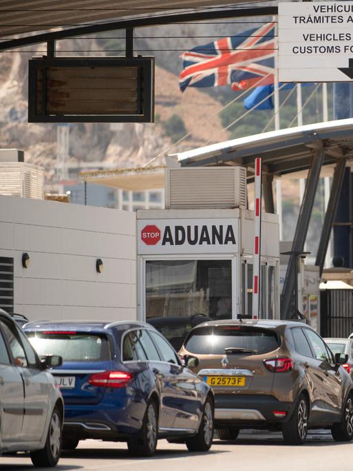 Fahrzeuge überqueren die Grenze von Spanien zu Gibraltar. Im Hintergrund weht die britische Flagge. Fahrzeuge überqueren die Grenze von Spanien zu Gibraltar. Im Hintergrund weht die britische Flagge.