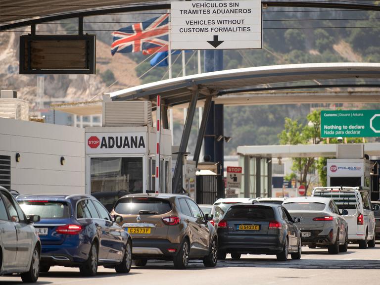 Fahrzeuge überqueren die Grenze von Spanien zu Gibraltar. Im Hintergrund weht die britische Flagge. Fahrzeuge überqueren die Grenze von Spanien zu Gibraltar. Im Hintergrund weht die britische Flagge.