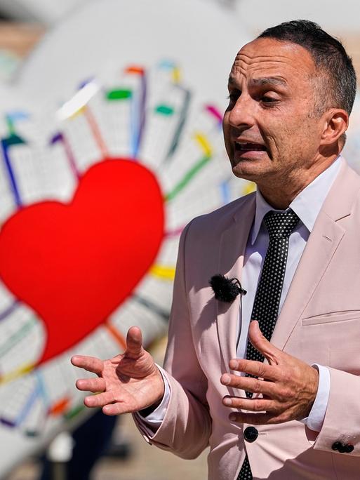 Der ESC-Experte Dean Vuletic gibt in der ESC-Woche am 16.5.2025 in Basel ein Interview. Im Hintergrung ist eine Deko mit bunten Herzen zu sehen.