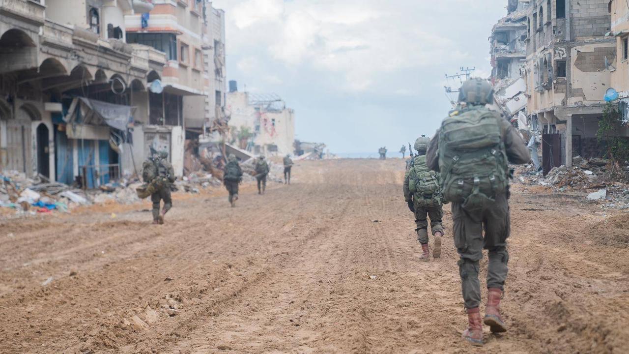 Soldaten der israelischen Armee laufen durch eine zerstörte Strasse in Gaza-Stadt.