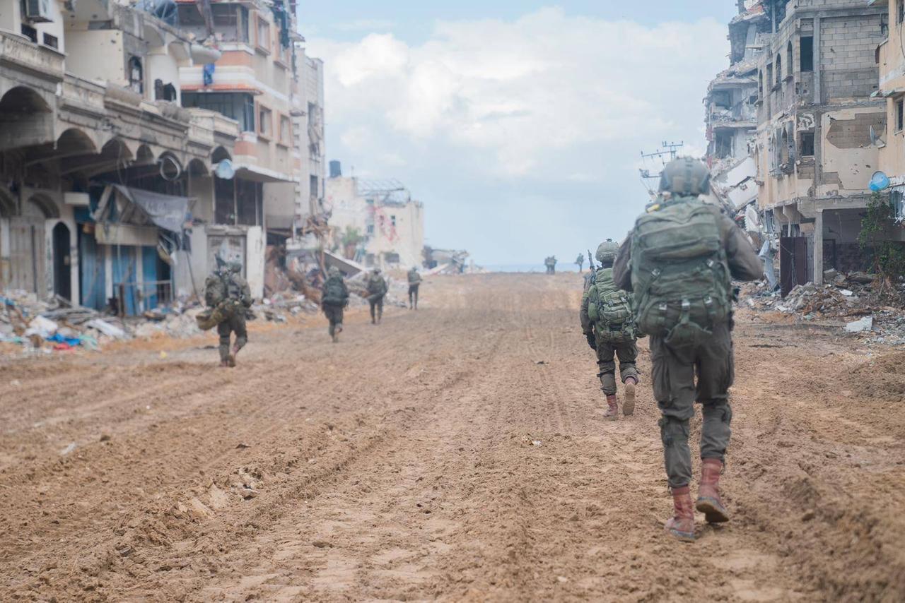 Soldaten der israelischen Armee laufen durch eine zerstörte Strasse in Gaza-Stadt.