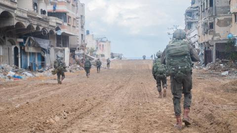 Soldaten der israelischen Armee laufen durch eine zerstörte Straße in Gaza-Stadt.