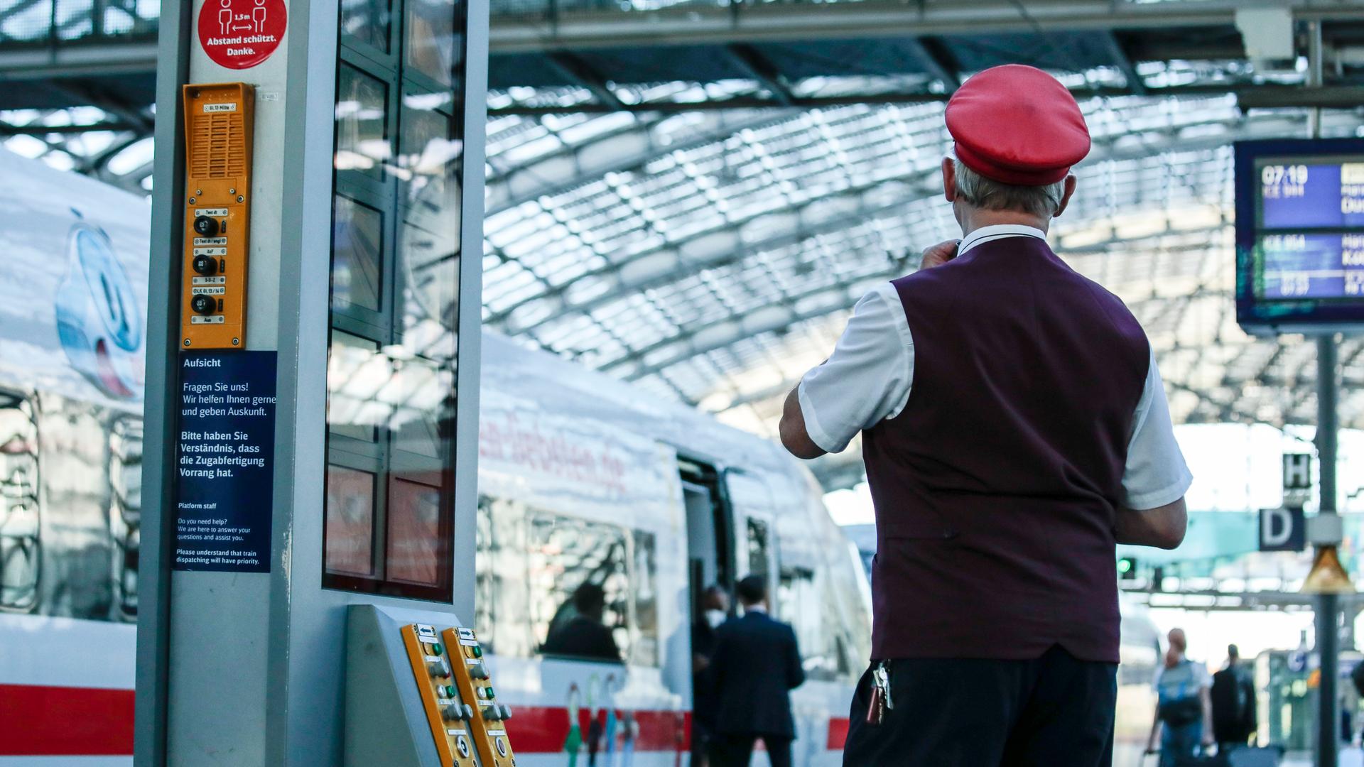 Ein Schaffner gibt das Abfahrtszeichen für einen ICE auf dem Bahnsteig im Berliner Hauptbahnhof. Ein Schaffner gibt das Abfahrtszeichen für einen ICE auf dem Bahnsteig im Berliner Hauptbahnhof.