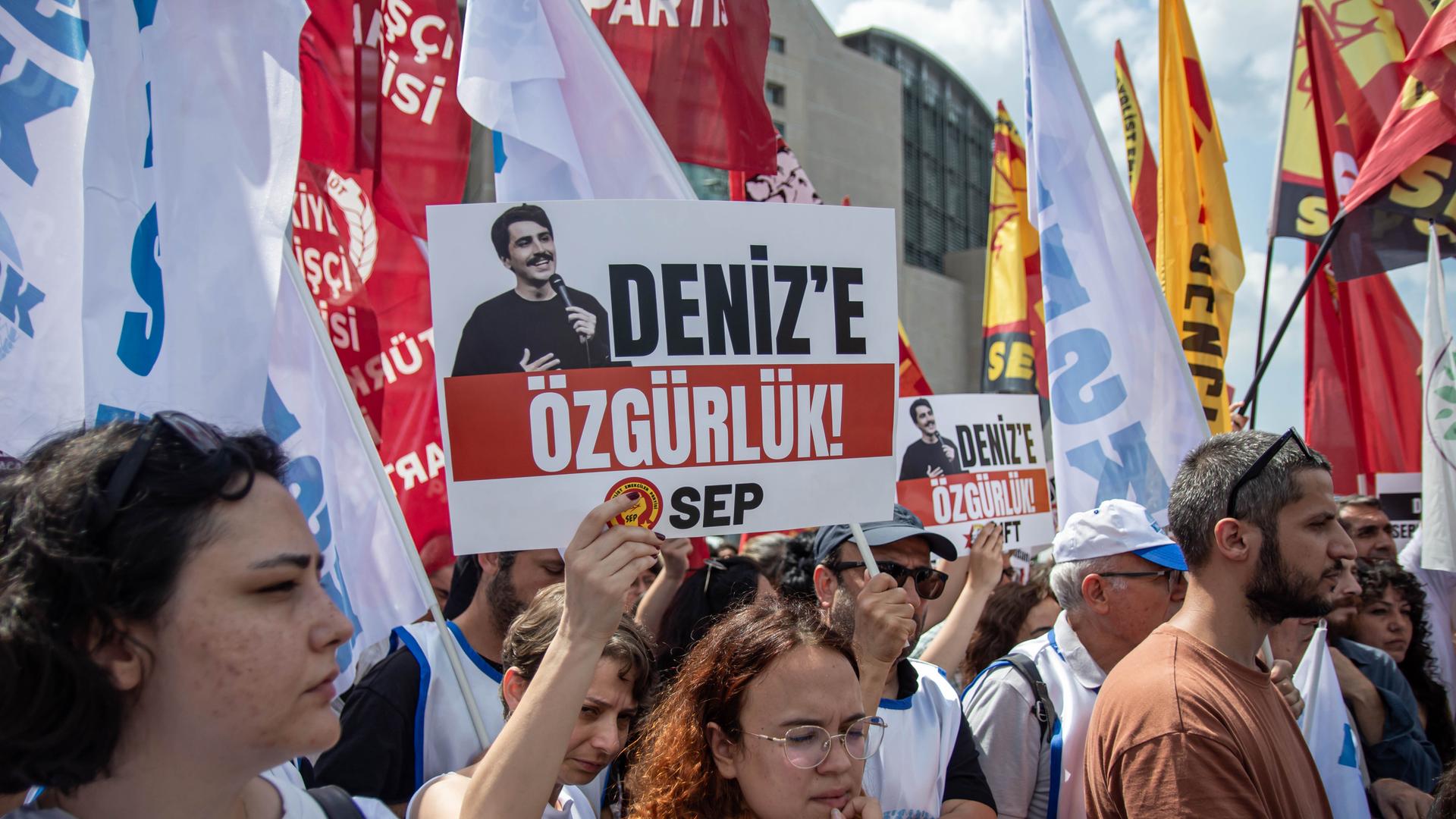 Viele Menschen stehen auf einem Platz, sie halten Schilder und Banner hoch. Viele Menschen stehen auf einem Platz, sie halten Schilder und Banner hoch.