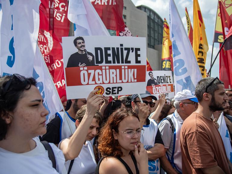 Viele Menschen stehen auf einem Platz, sie halten Schilder und Banner hoch. Viele Menschen stehen auf einem Platz, sie halten Schilder und Banner hoch.