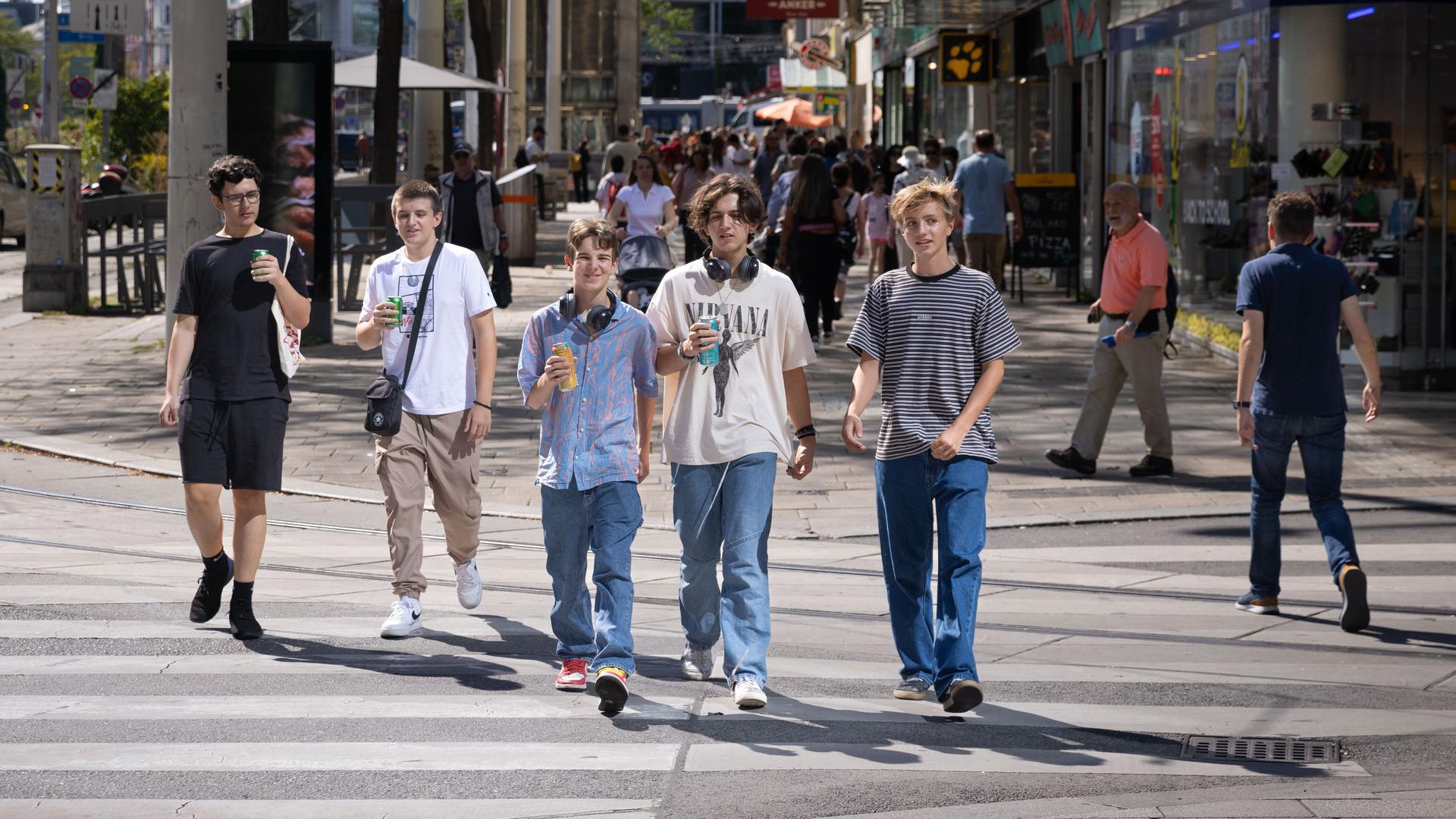 Jugendliche gehen eine Straße entlang.