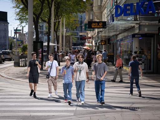 Jugendliche gehen eine Straße entlang.