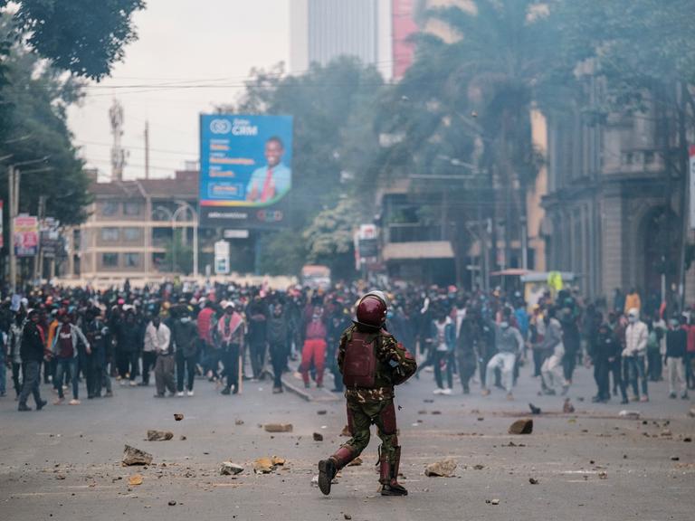 Ein Polizist steht Demonstranten in einer Straße in Nairobi gegenüber.