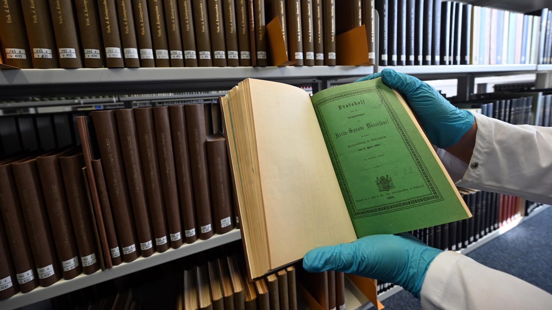 Eine Mitarbeiterin der Universitäts- und Landesbibliothek Düsseldorf hält ein Buch in den Händen, das möglicherweise mit Arsen belastet ist. Eine Mitarbeiterin der Universitäts- und Landesbibliothek Düsseldorf hält ein Buch in den Händen, das möglicherweise mit Arsen belastet ist.