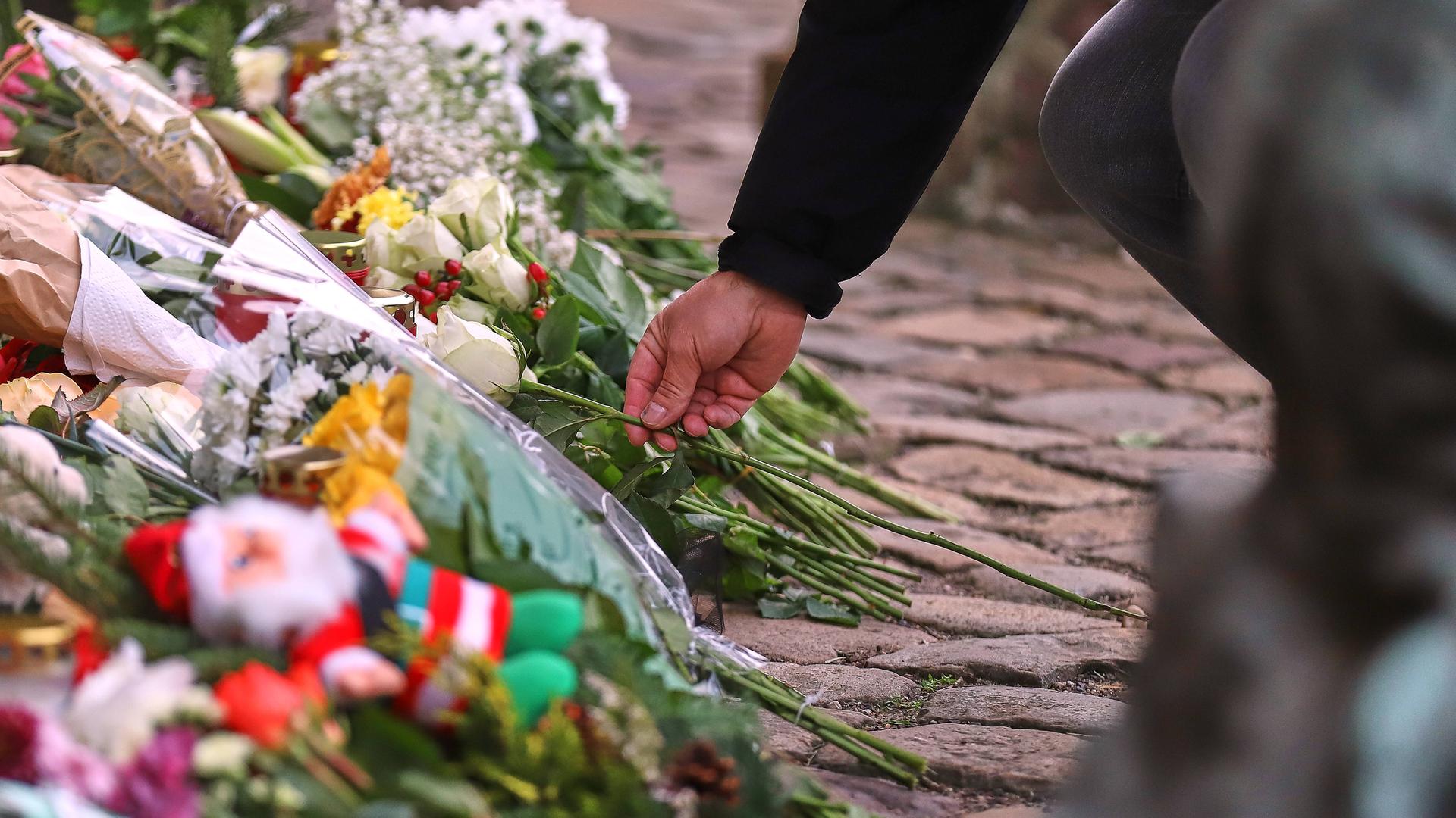 Ein Mensch legt eine Blume vor der Johanniskirche in Magdeburg zu vielen anderen Blumen ab, um den Opfern des Anschlags vom 20. Dezember zu gedenken.