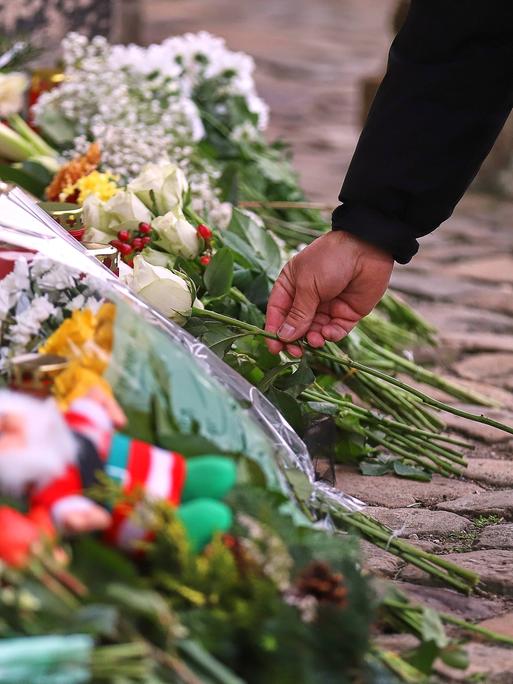 Ein Mensch legt eine Blume vor der Johanniskirche in Magdeburg zu vielen anderen Blumen ab, um den Opfern des Anschlags vom 20. Dezember zu gedenken.