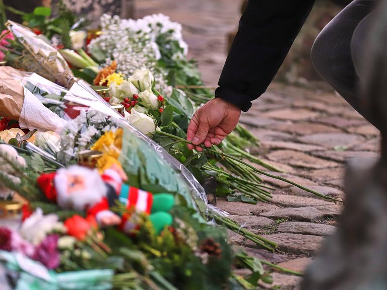 Ein Mensch legt eine Blume vor der Johanniskirche in Magdeburg zu vielen anderen Blumen ab, um den Opfern des Anschlags vom 20. Dezember zu gedenken.