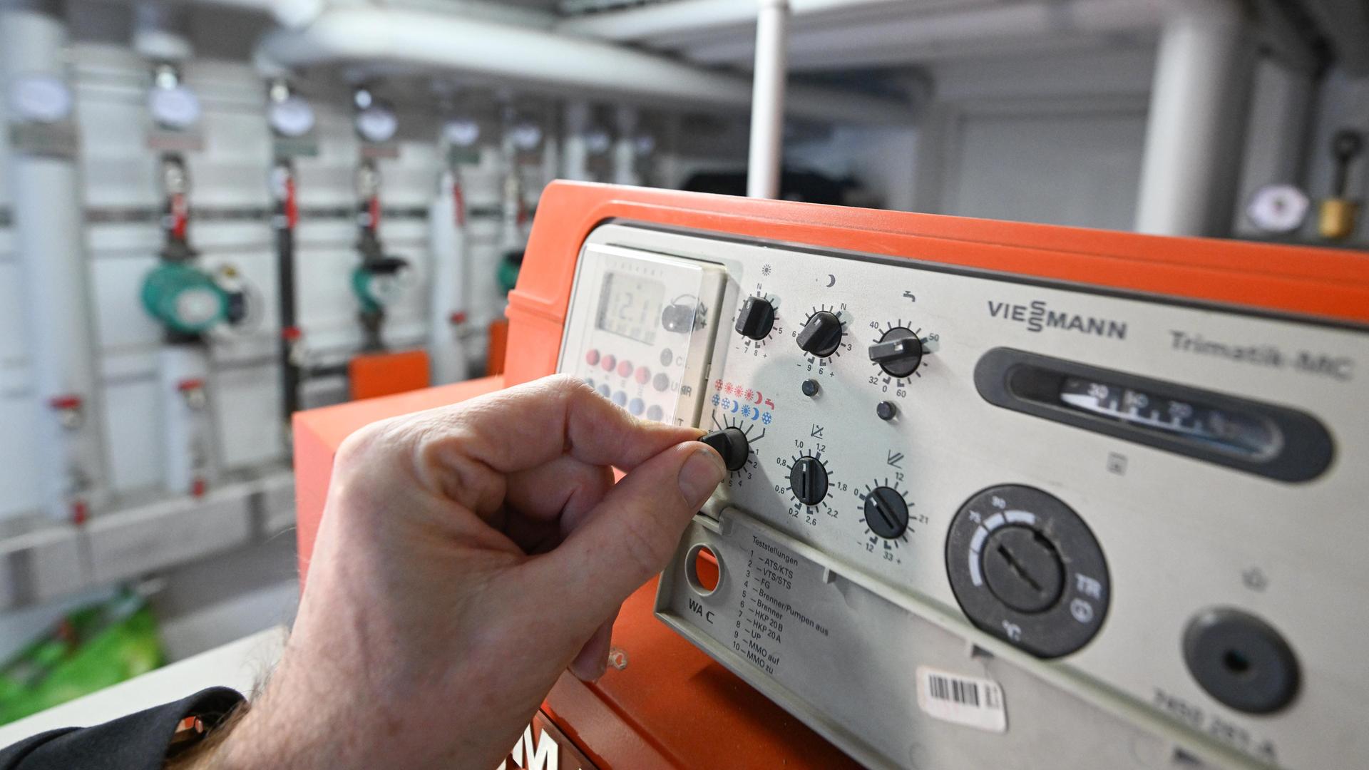 Eine Hand reguliert die Steuerungsanlage einer Gasheizung in einem Mehrfamilienhaus. Eine Hand reguliert die Steuerungsanlage einer Gasheizung in einem Mehrfamilienhaus.