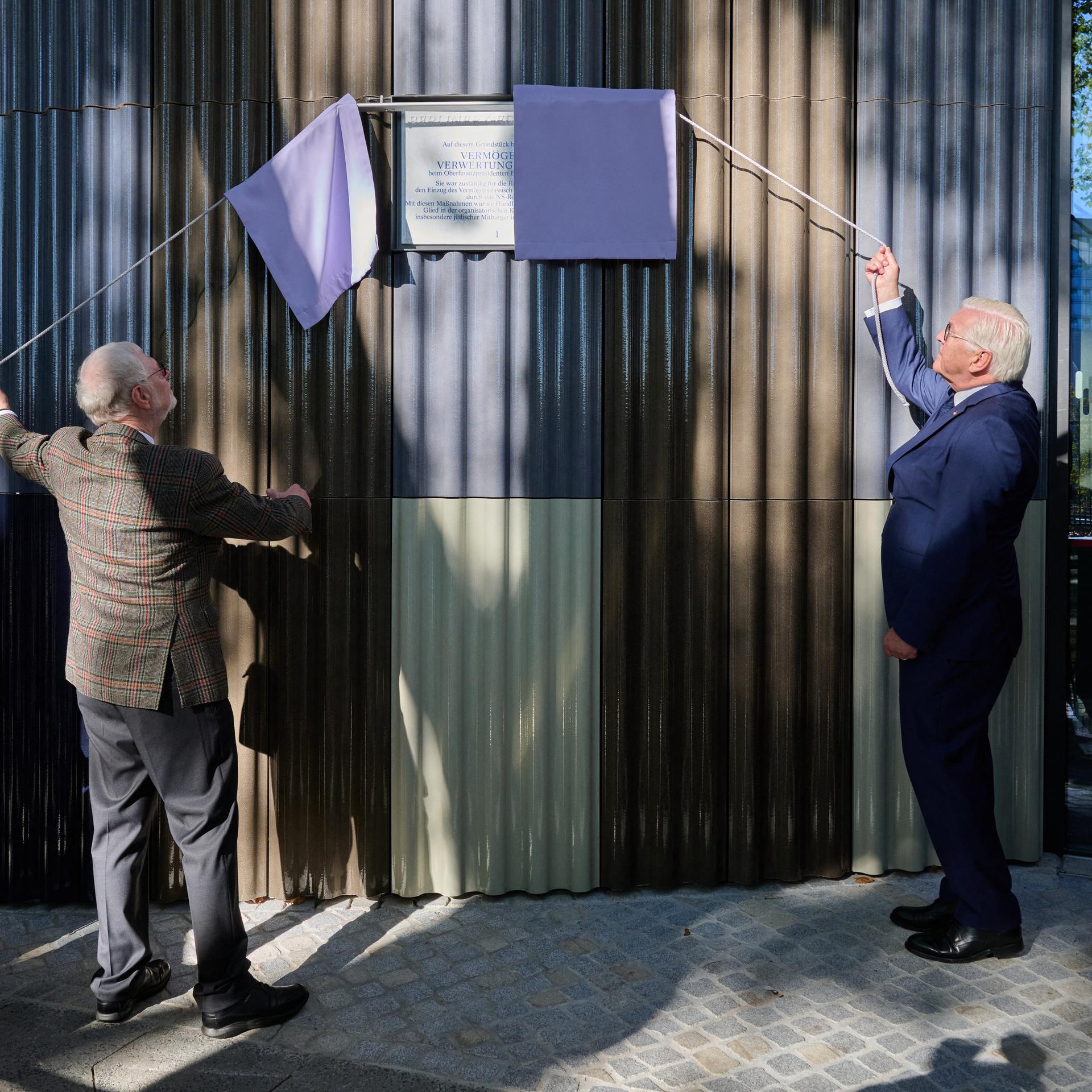 Thomas Abel (3.v.l.) vom Verein "Gleis 69" und Bundespräsident Frank-Walter Steinmeier enthüllen bei der Wiedereinweihung die Gedenktafel am Standort der einstigen Berliner Vermögensverwertungsstelle des NS-Regimes.