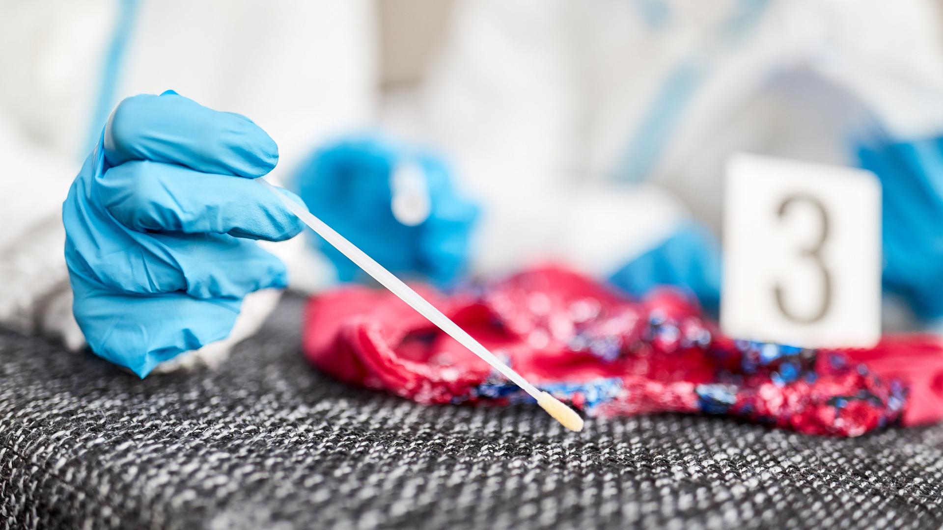 Kriminaltechniker nehmen mit einem Wattestäbchen eine DNA-Probe.