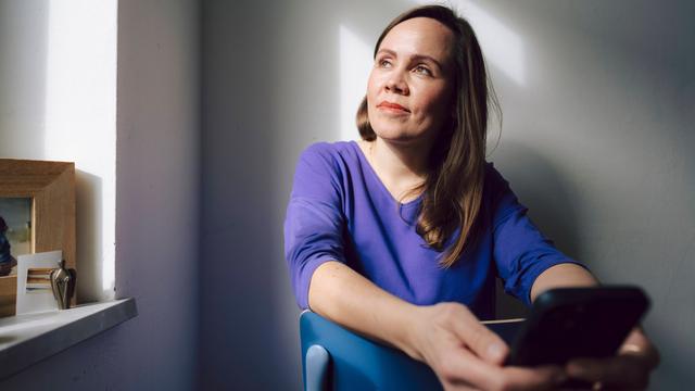 Das Foto zeigt eine Frau mit einem Handy. Sie ist allein.