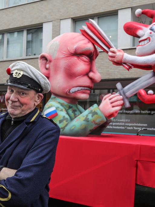 Der russische Praesident Wladimir Putin spiesst den Hoppeditz mit einem Schwert auf. Die Düsseldorfer Karnevalsfigur wiederum schlägt dem in Militaeruniform gekleideten Putin mit einer Narrenpritsche auf den Kopf.