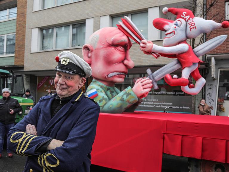 Der russische Praesident Wladimir Putin spiesst den Hoppeditz mit einem Schwert auf. Die Düsseldorfer Karnevalsfigur wiederum schlägt dem in Militaeruniform gekleideten Putin mit einer Narrenpritsche auf den Kopf.