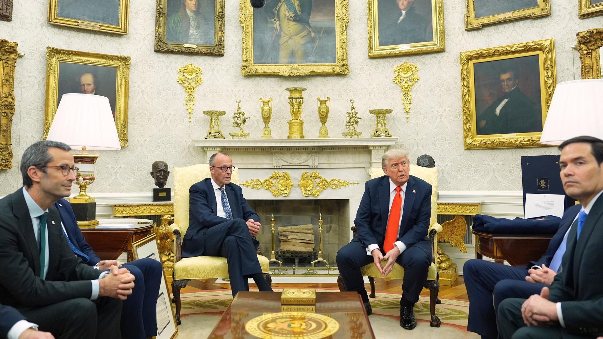 Donald Trump und Friedrich Merz sitzen im Oval Office nebeneinander, während US-Außenminister Marco Rubio zuhört.