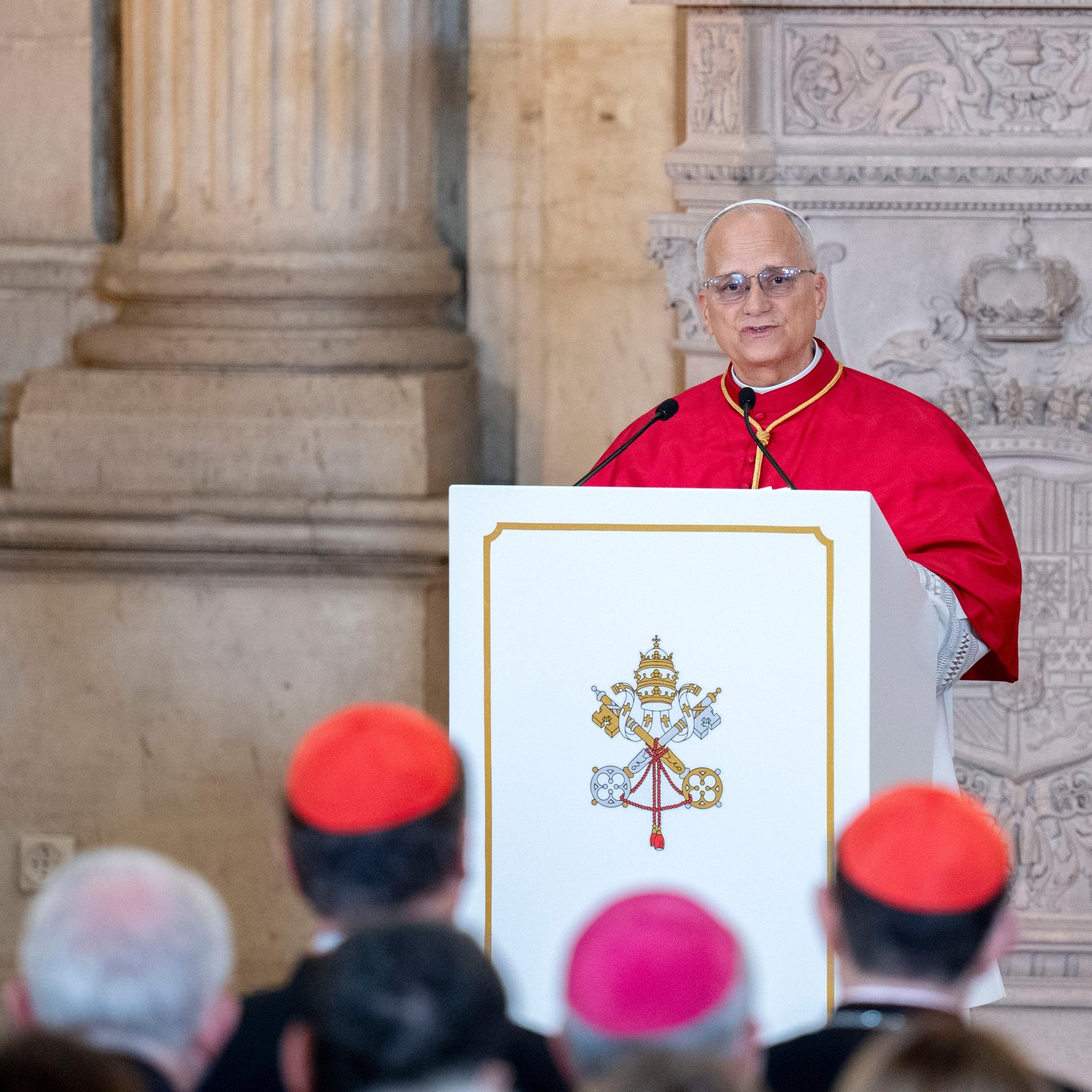 Das Bild zeigt Papst Leo XIV. an einem Redepult. Er spricht zu zahlreichen Zuhörern. die schemenhaft im Vordergrund zu sehen sind.